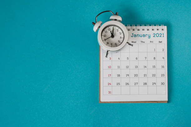 istock white analog alarm clock on calendar with grunge blue background with copy space, business meeting schedule, travel planning or project milestone and reminder ,New year holiday , celebration concept 1293013817