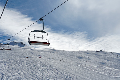 Empty chair lifts in ski resort Switzerlnand closing up because of corona virus. The last skiers are on the slope. The resort is more or less abandoned due to official ban of ski resorts operation.