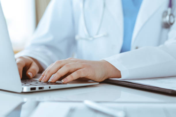 istock Unknown woman-doctor typing on laptop computer while sitting at the table. Medicine concept 1293017846