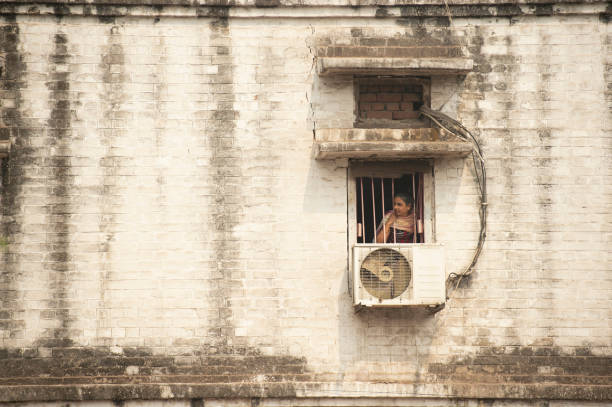 A young girl is looking through the window during the Covid-19 lockdown in India. New Delhi, India, November 11, 2020. A young girl is looking through the window during the Covid-19 lockdown in India. Delhi is in the midst of a third wave of COVID-19, breaking a local daily record of 8,593 cases on November 12. prison lockdown stock pictures, royalty-free photos & images