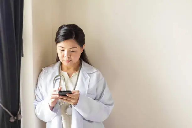 Photo of True chinese female doctor communicate with her patient using phone