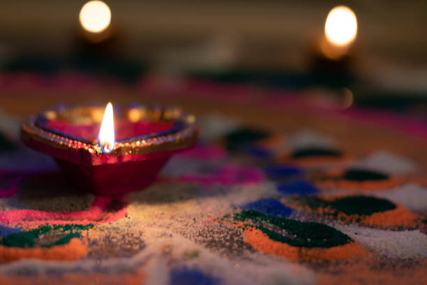 Bright Golden Yellow Flames Emitting From Exotic Earthen Clay Lamps Diya Or Deep On Beautiful Traditional Rangoli At Dark Black Night Hours During Festival Diwali New Year Celebration India With Bokeh Lights In The Background llamas amarillas doradas brillantes que emiten de lámparas de arcilla earthen exóticas diya o profundas en el hermoso rangoli tradicional en las horas de noche negra oscura durante el festival diwali celebración de año nuevo india con luces bokeh en el