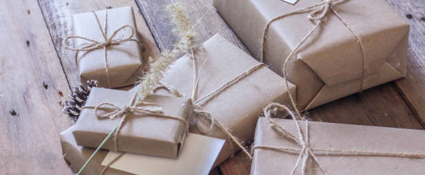 istock Christmas gift box Use brown recycled paper and notepad on a wooden table. 1293035591