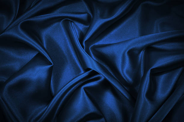 istock Abstract blue black background. Blue silk satin texture background. Beautiful soft wavy folds on shiny fabric. Dark elegant background for your design. 1293037607
