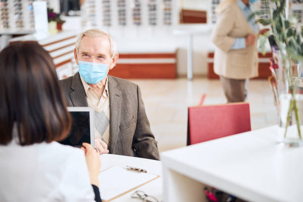 istock Man in a face mask looking at the optician 1293039082