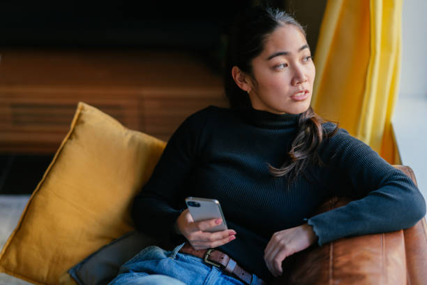 istock Young woman relaxing on sofa while holding smart phone 1293043538