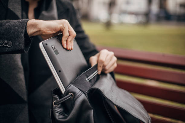 istock Man putting laptop in backpack in park 1293052650
