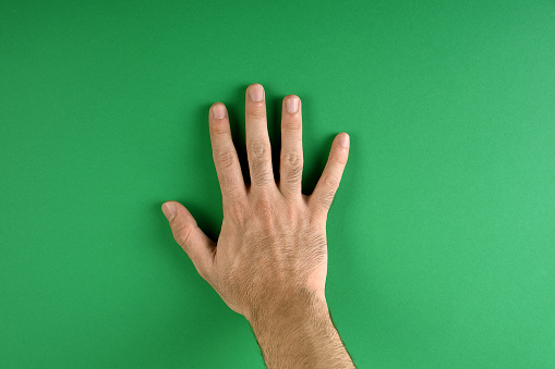 Directly above a male hand on the green color background with copy space