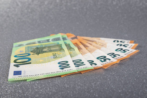 istock 100 and 50 Euro bank notes in a row on silver glitter background 1293055412