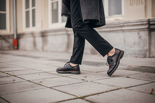One man, modern young man in leather shoes, walking on the street in city.