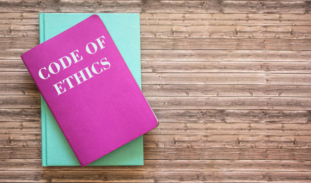 istock Code of Ethics - the text is written on a notebook that lies on a wooden table. 1293058541