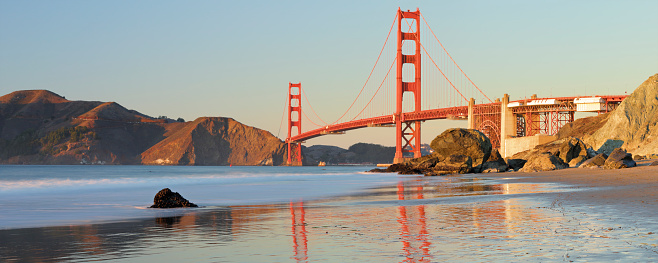 Panoramic view of the Golden Gate bridge at sunset as seen from Marshall’s beach (San Francisco, California).