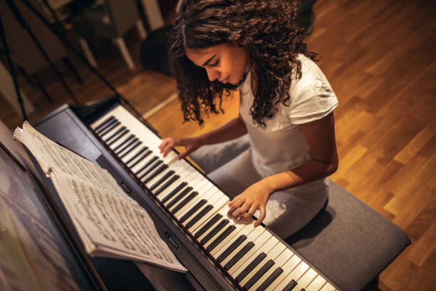 Girl playing piano at home Girl learning to play piano during coronavirus pandemic girl playing piano stock pictures, royalty-free photos & images