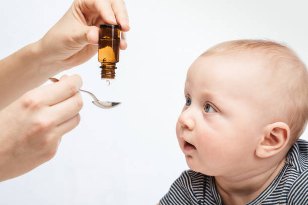 Mother feeding baby boy with liquid medicine Mother feeding baby boy with vitamin or liquid medicine using spoon child liquid medicine stock pictures, royalty-free photos & images