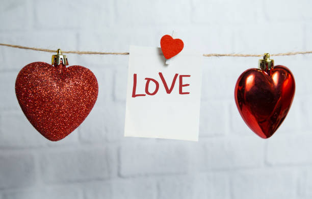 istock red hearts and white card hang on a thread on a white brick background 1293069061
