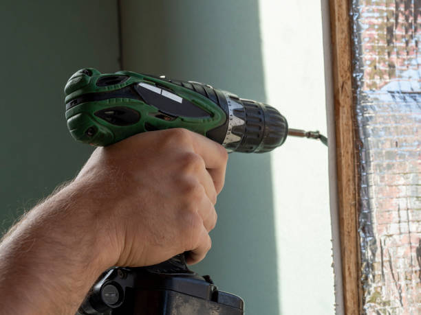 istock a man is holding a screwdriver and twisting the screw into the drywall. selective focus 1293069106