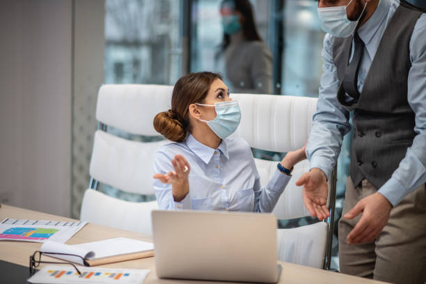 istock Two businesspersons with their face masks trying to fix issue on files. 1293069161