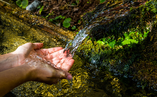 Lavarse las manos y beber de un manantial con agua de montaña clara y fría photo
