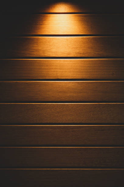istock Yellow light radiating from above on the wooden floor, copy space 1293070246
