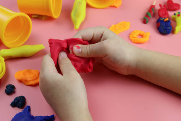 istock Child sculpts from colored plasticine on the table, hands close-up 1293074281