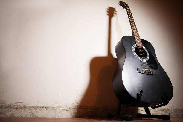 istock acoustic guitar on vintage plaster wall background with shadow. Space for text 1293074310