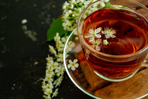 istock A cup of flower tea with spring cherry blossom on a black background. Copy space 1293080942