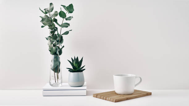 istock A mug, a stack of books, a wooden board and a transparent vase with eucalyptus branches. Eco-friendly materials in interior decor, minimalism. Copy space, mock up 1293099352