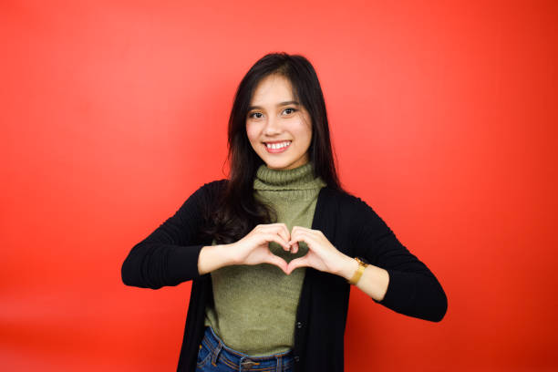 istock Young beautiful asian women using black sweater with red isolated background 1293099411