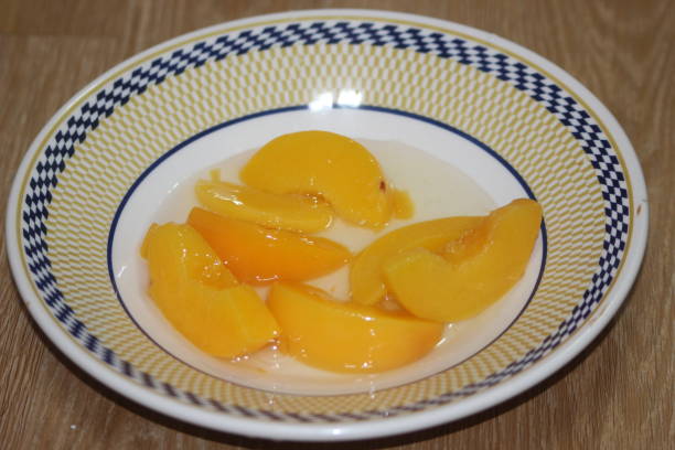 istock Canned peaches halves sprinkled with syrup in white plate. 1293099457