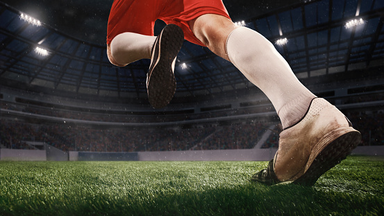Excited running, aspirated. Football or soccer player on full stadium and flashlights background. Cropped close up with copyspace. Concept of sport, competition, winning, action and motion.