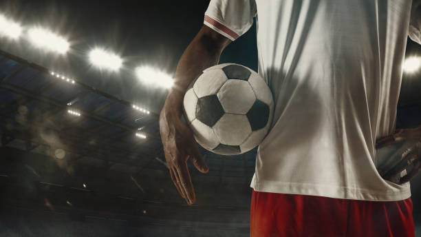 istock Football or soccer player on full stadium and flashlights background 1293105100