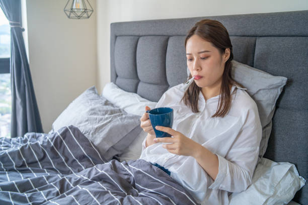 istock Sick Woman Lying on Bed with Thermometer 1293107447