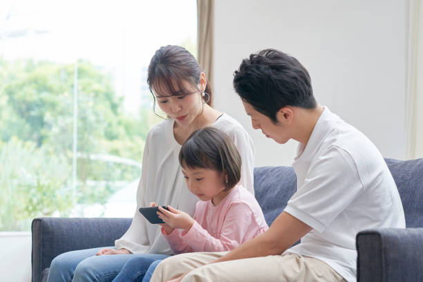 ソファでスマートフォンを使ったアジアの家族 - 日本人　親子 ストックフォトと画像