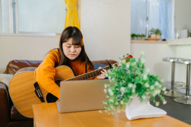istock Young woman learning playing acoustic guitar via online training classes at home 1293116901