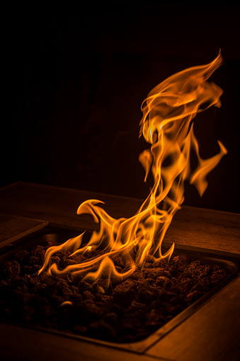 Fire dances in the dark from a gas fire pit with focus on the flames