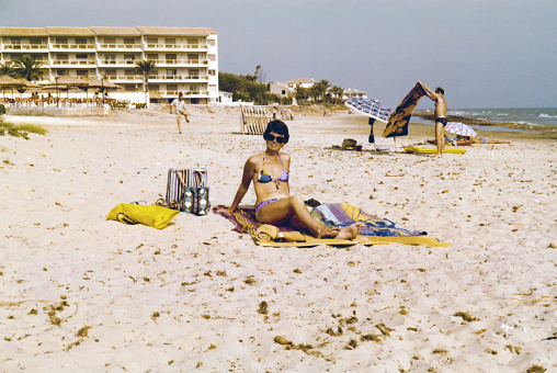 Vintage 1980s image, young woman enjoying a day at the beach of Antibes, France.