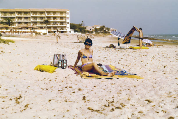 Young woman enjoying a day at the beach Vintage 1980s image, young woman enjoying a day at the beach of Antibes, France. sunbathing photos stock pictures, royalty-free photos & images