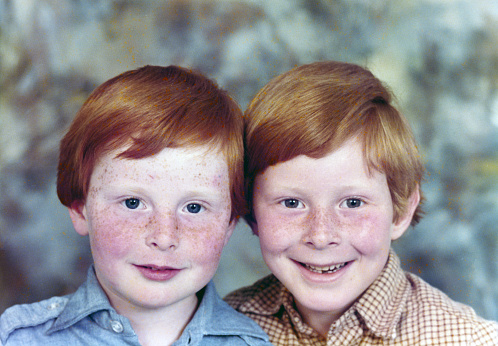 Early 1980s portrait of two little brothers, side by side,  with ginger hair and freckles.