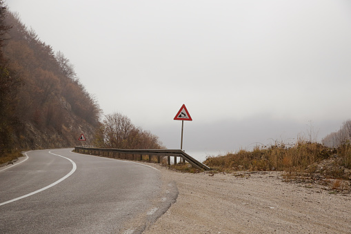 Urban road through nature in Tuscany on a foggy cloudy day.