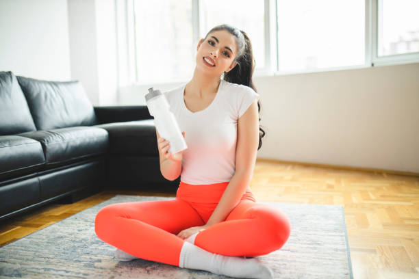 istock Woman relaxing after home workout and drinking water 1293153787