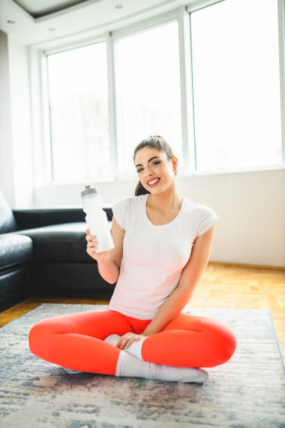 istock Woman relaxing after home workout and drinking water 1293153820
