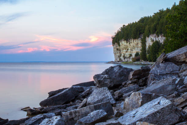 Michigan Waterfront Landscape At Fayette State Park Gorgeous harbor landscape with dock pilings and lime stone cliffs at the horizon of Fayette State Park on the coast of Lake Michigan. michigan photos stock pictures, royalty-free photos & images