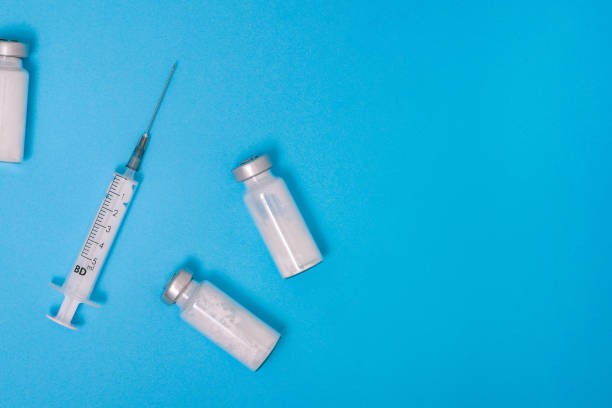 istock Pharmaceutical glass ampoule. Medical syringe on a blue background with copy space. White powder for injection. Antibiotic for the treatment of diseases, infections and coronavirus. Covid-19 vaccine 1293160601