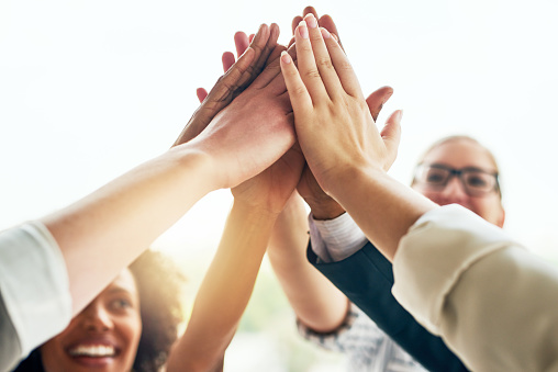 Cropped shot of a group of unrecognizable businesspeople high fiving while standing in their office