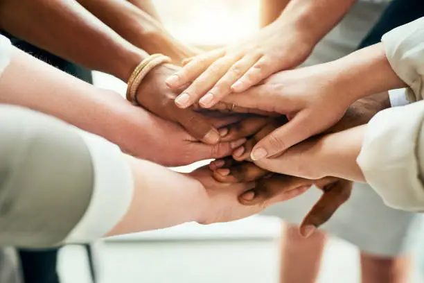 Cropped shot of a group of unrecognizable businesspeople standing in the office with their hands in a huddle