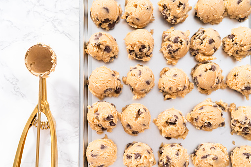Homemade chocolate chip cookies dough scoops on a baking sheet.