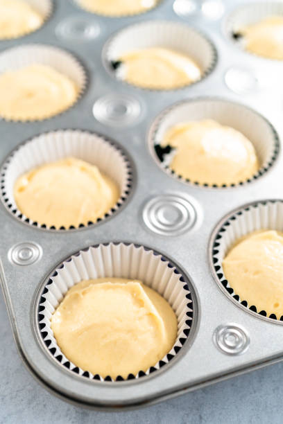istock Vanilla cupcake batter in foil cupcake liners to bake Mardi Gras vanilla cupcakes. 1293162267
