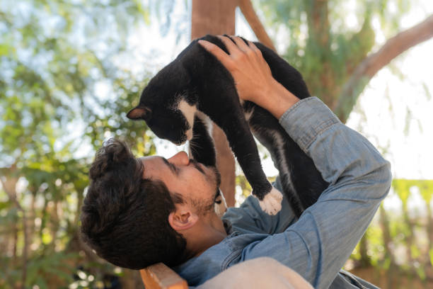 young man and black cat look at each other. close up