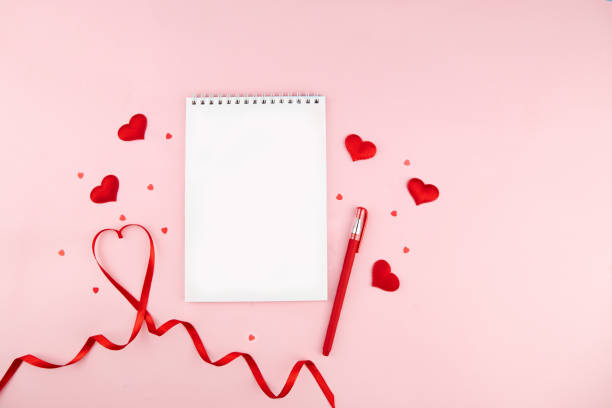 赤いハートの形の装飾とピンクの背景に赤いリボンを持つノートブック。結婚式、ロマンチックでハッピーバレンタインデーの休日の概念。 - love letter ストックフォトと画像