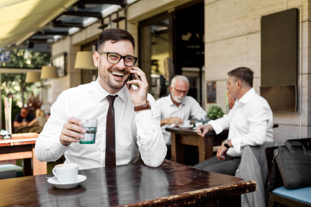 istock Young businessman in sidewalk cafe talking on a smart phone 1293182595